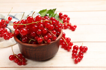 Fresh red currant berries in bowl on white wooden table, closeup