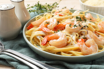 Delicious pasta with shrimps and creamy sauce served on table, closeup