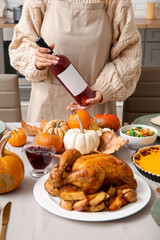 Woman with wine at dining table set for Thanksgiving Day, closeup