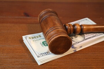 Alimony. Judge's gavel and stack of money on wooden table, closeup