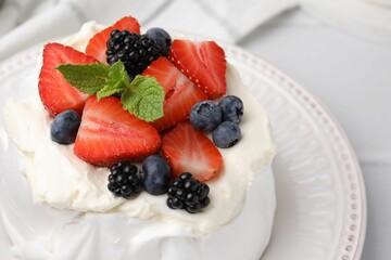 Pavlova cake (meringue dessert) with whipped cream, fresh berries and mint on white table, closeup