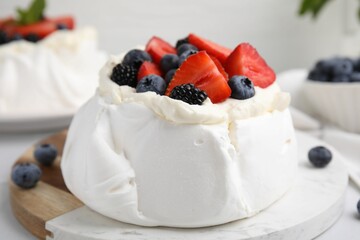 Pavlova cake (meringue dessert) with whipped cream and fresh berries on table, closeup