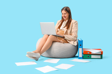 Young pregnant businesswoman working with laptop on blue background