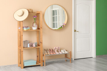 Stylish hallway interior with wooden storage shelf, mirror, footwear collection and spring flowers