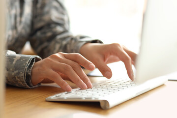 Female soldier working with computer at table in headquarters, closeup