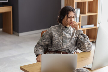 Female African-American soldier with headset working at table in headquarters