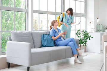 Female medical interns using tablet computer in clinic