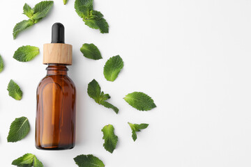 Bottle of essential oil and mint isolated on white, top view