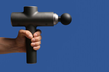 Male hand with percussive massager on color background, closeup