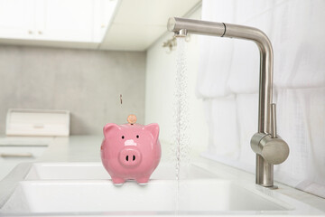 Water saving concept. Coins falling into piggy bank and stream of water flowing from tap in kitchen