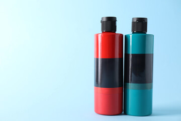 Acrylic paints of different colors on light blue background, space for text