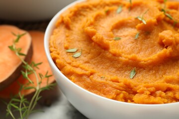 Delicious mashed sweet potatoes in bowl and microgreens on table, closeup