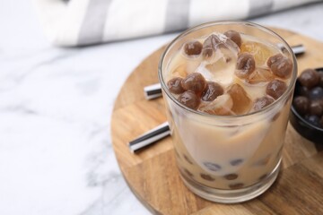 Tasty milk bubble tea in glass, tapioca pearls and straws on white marble table, closeup. Space for text