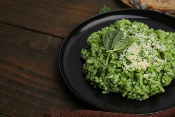 Delicious spinach risotto with parmesan cheese on wooden table, closeup. Space for text