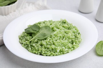Delicious spinach risotto on light grey table, closeup