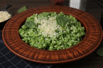 Delicious spinach risotto with parmesan cheese on wooden table, closeup