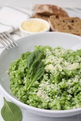 Delicious spinach risotto with parmesan cheese served on white tiled table, closeup