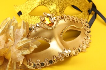 Golden carnival masks on yellow background, closeup