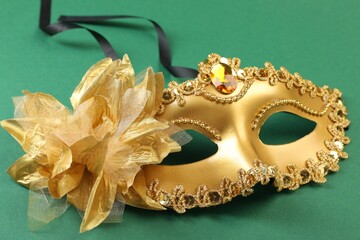 One golden carnival mask on green background, closeup