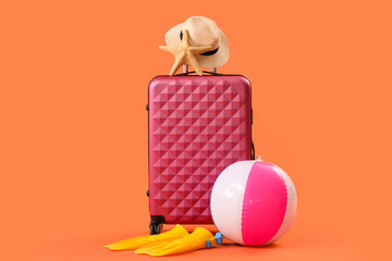 Suitcase, inflatable ball and flip-flops on orange background. Travel concept