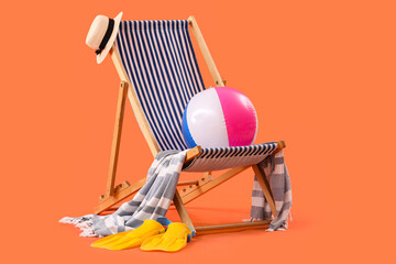 Deck chair and beach accessories on orange background. Travel concept