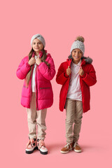 Cute little happy children in winter clothes on pink background