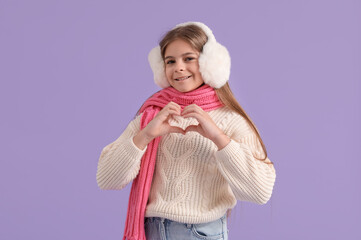 Cute little stylish happy girl in winter clothes on purple background