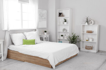 Interior of modern stylish comfortable bedroom with shelving units and different houseplants