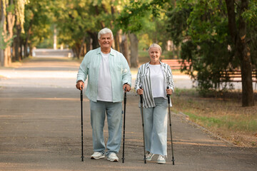 Obraz premium Mature woman and man with walking poles in park