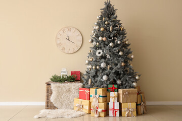 Christmas tree with presents and basket near beige wall in room