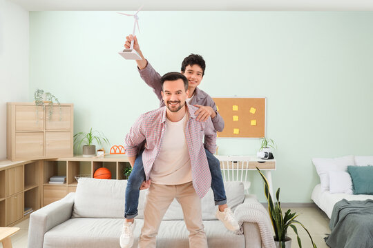 Teenage boy with wind turbine model and his father having fun at home