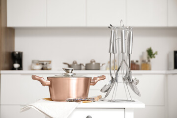 Cooking pot with utensils on table in kitchen, closeup