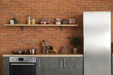Interior of modern kitchen with silver fridge, counters and shelf