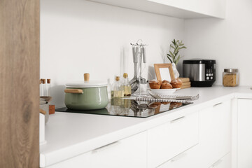 Cooking pot on stove with utensils in light kitchen