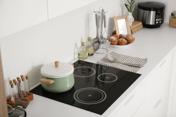 Cooking pot on stove with utensils in light kitchen