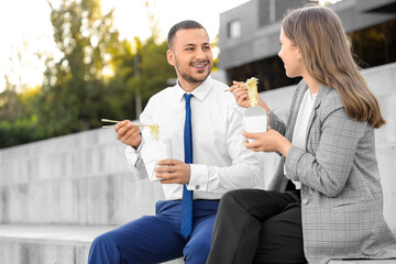 Business colleagues eating Asian noodles during lunch break outdoors