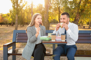 Business colleagues having lunch on bench in park