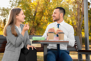 Business colleagues having lunch on bench in park