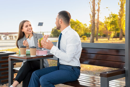 Business colleagues having lunch on bench in park