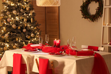 Dining table set for Christmas with burning candles in dark room