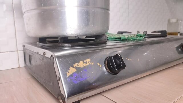 Turning off the gas stove in the kitchen with a pan on it