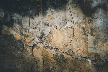 A wall with a lot of cracks and holes. The wall is made of concrete and has a rough texture