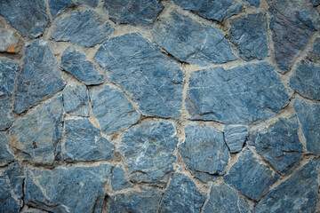 A wall made of blue stones. The stones are rough and uneven