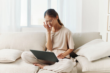 Fototapeta premium Smiling Woman Typing on Laptop, Enjoying a Cozy and Modern Work-from-Home Lifestyle