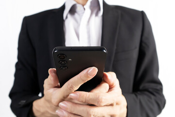 Businessman in black suit standing holding mobile phone to view work data and check work