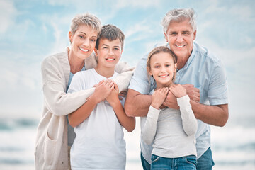 Portrait, grandparents and grandkids embracing on beach together for holiday, travel or vacation....