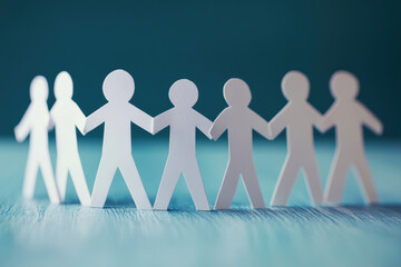 Paper cutout figures holding hands in a line, representing teamwork, unity, and support on a blue background.