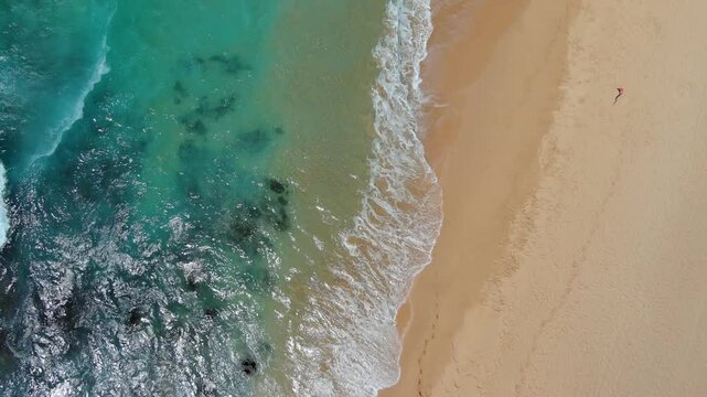 overhead aerial footage of the waves rolling into the silky brown sands of Sandy beach in Honolulu Hawaii USA