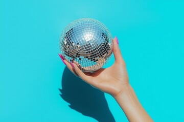 A hand holding a silver disco ball  