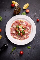 cooking tuna carpaccio - cherry tomato pieces on a plate with raw tuna fillet slices